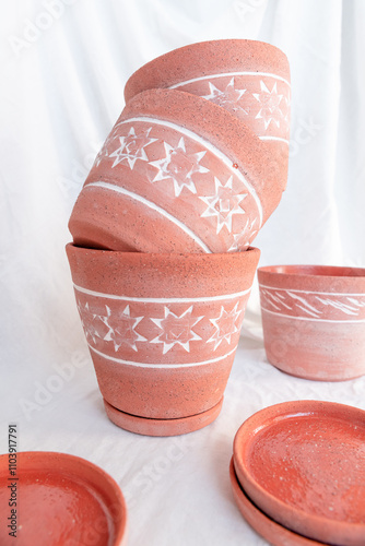 Stacked terracotta flower pots with a repeating 8-pointed star design, showcasing the unique texture and stacked arrangement