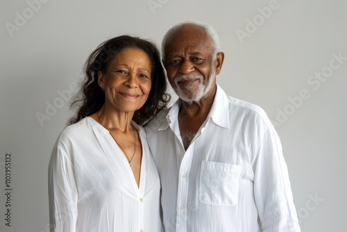 Portrait of a joyful mixed race couple in their 80s wearing a classic white shirt over plain white digital canvas