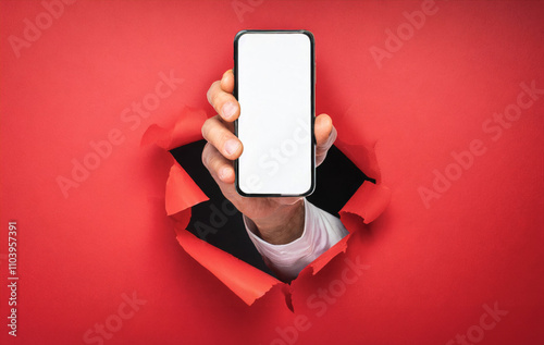 Hand holds a smartphone with white display breaks through a red wall. Concept of message, announce
