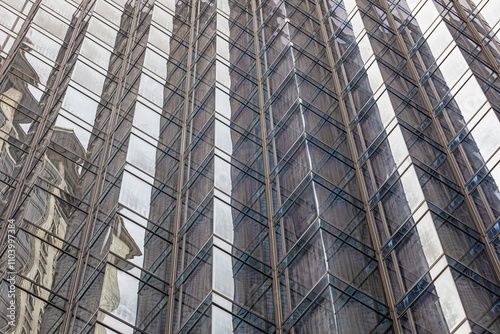 Close-up of a modern skyscraper facade with reflective glass panels showcasing abstract urban reflections