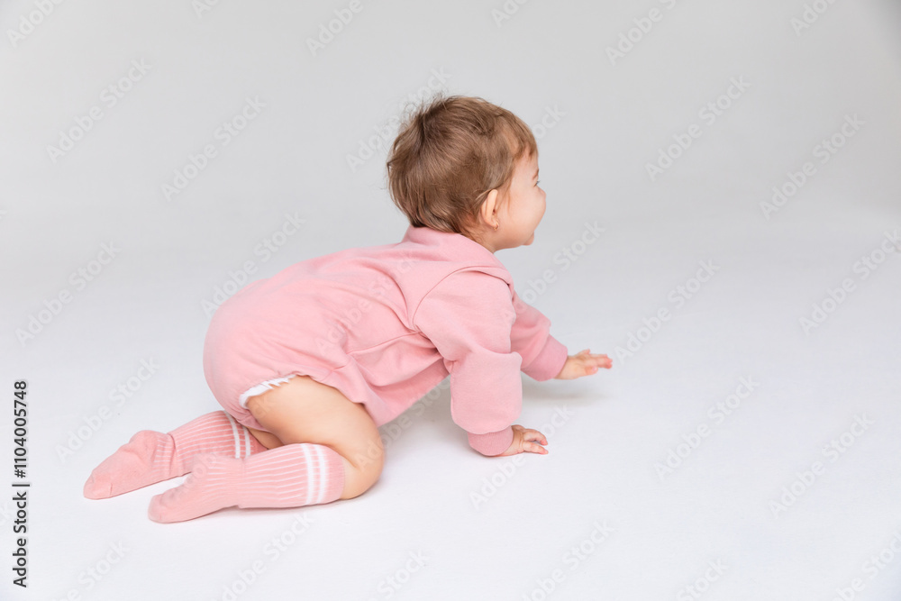 Side view baby child girl in a pink bodysuit and socks crawling over white isolated background. Childhood and fashion. Birthday party concept. High quality photo Side view baby child girl in a pink bodysuit and socks crawling over white isolated background. Childhood and fashion. Birthday party concept. High quality photo