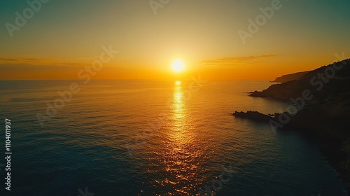 Vibrant sunset over calm ocean and rocky coast.