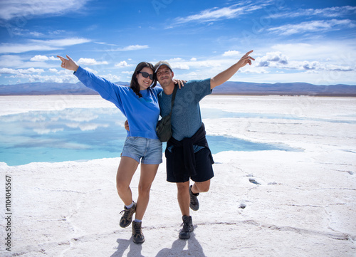 Happy young man and woman couple in a fun attitude posing in the spectacular Salinas Grandes of Argentina enjoying their trip to South America.