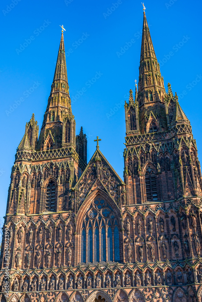 Fototapeta premium The western spires above the entrance of Lichfield Cathedral with a beautiful blue sky