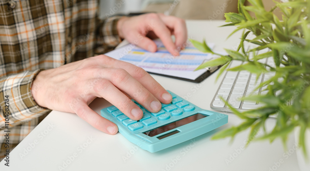 Close-up of hands using calculator and budget documents on a desk, personal finance concept