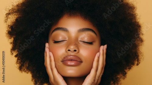 A woman with an afro hairstyle embracing a moment of peaceful reflection, with closed eyes and hands on cheeks, representing serenity and self-contentment. photo