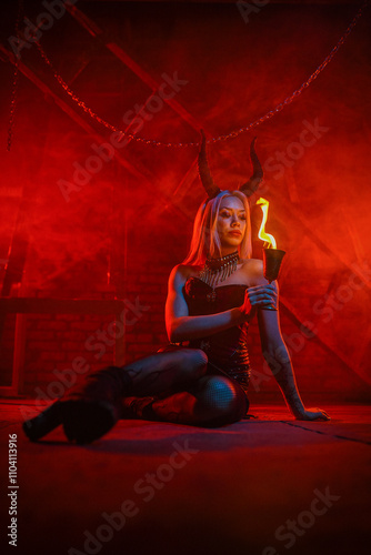 A beautiful woman with devilish horns on a red blood like smoky hell concept background. photo