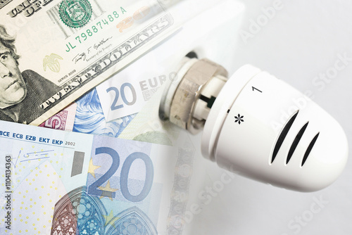 Thermostat set to zero with snowflake icon and money. Rising home heating costs in winter. Cold weather expenses. Radiator background with banknotes highlighting energy bills. photo