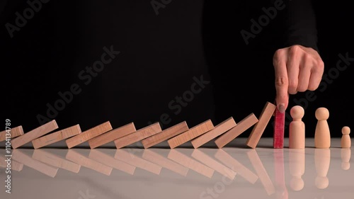 Falling dominos are stopped by a businesswoman’s hand, symbolizing protection an
