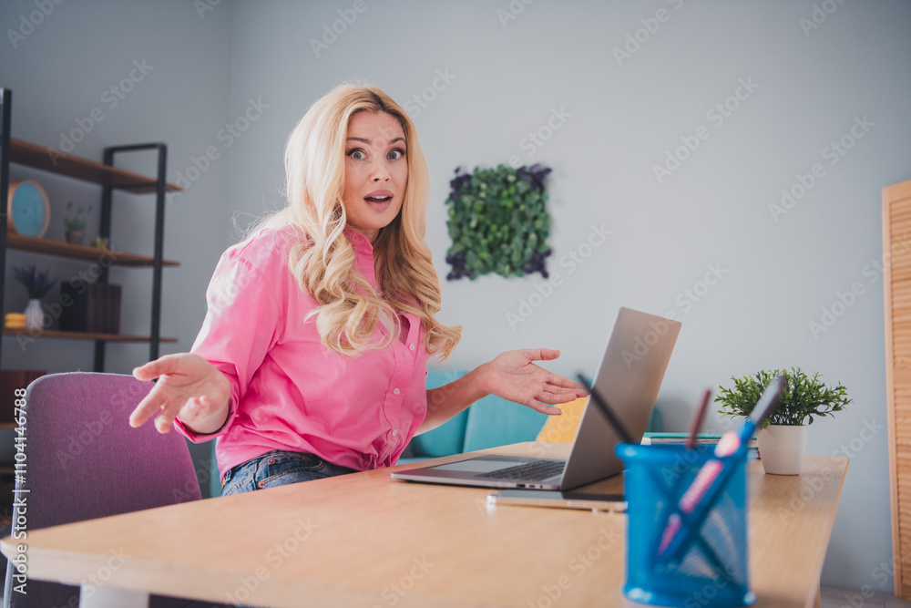 Surprised young woman working remotely on laptop in bright living room at home Surprised young woman working remotely on laptop in bright living room at home
