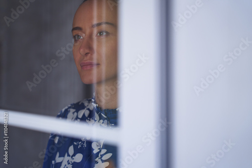 Contemplative woman looks through a window with soft focus photo