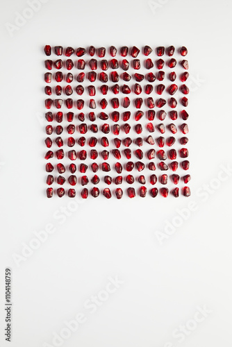 Geometric arrangement of pomegranate seeds on white surface photo