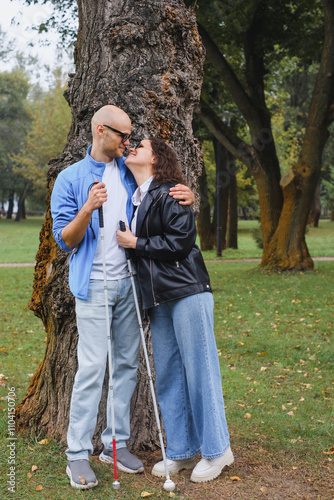 blind couple embracing in park with walking sticks and trees photo