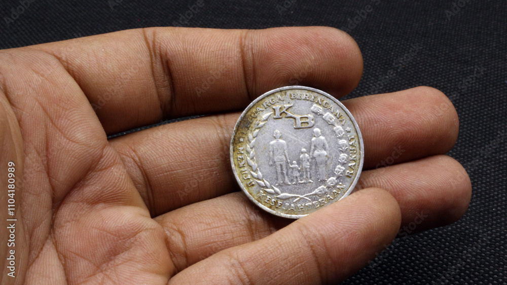Hand holding an old five rupiah coin Hand holding an old five rupiah coin