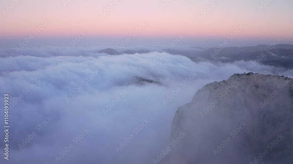 Aerial view of sunset-lit mountains covered in fog and clouds, revealing an epic natural scene with vibrant colors and dramatic atmosphere. Aerial view of sunset-lit mountains covered in fog and clouds, revealing an epic natural scene with vibrant colors and dramatic atmosphere.