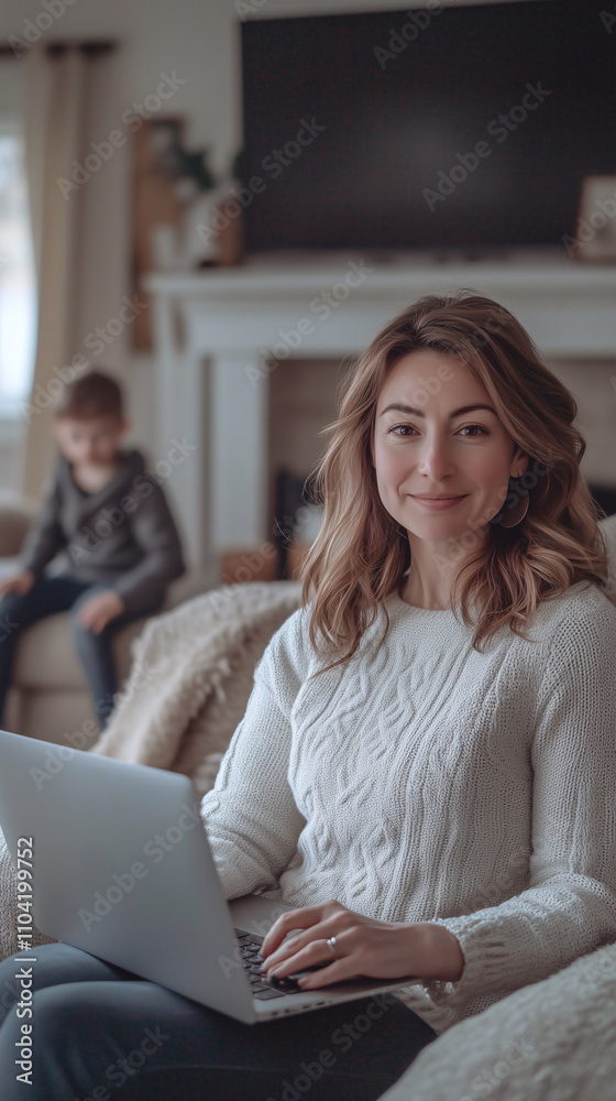 Young woman is working from home, using her laptop while her son plays in the background Young woman is working from home, using her laptop while her son plays in the background