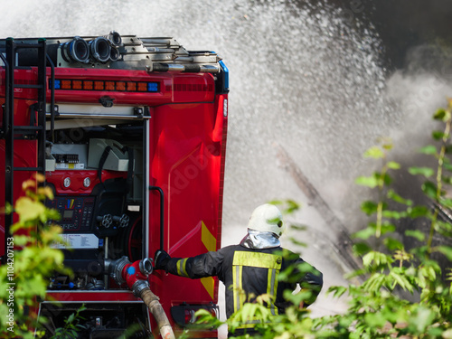 Standinding firefighter near fire engine against smoke environments during day time and real burning building.