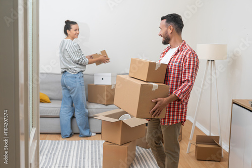 Married couple enjoys moving in new contemporary flat in another town together carrying and packing various carton boxes in accommodation living room