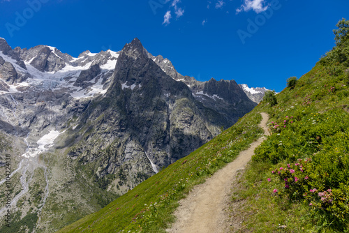 Val Ferret mountain landscape in the Alps. Tour du Mont Blanc beautiful scenic view from the hiking path on the way from Itlay to Switzerland. Alpine meadow and high snow peaks of the Alps on the sun photo