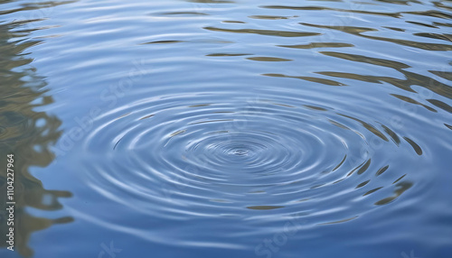 Closeup of water surface with ripples and reflections, against a blurred blue sky background