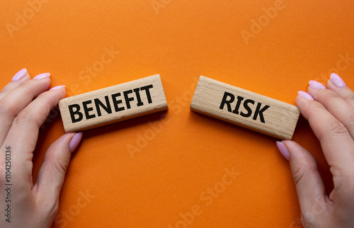 Fototapeta Naklejka Na Ścianę i Meble -  Risk or Benefit symbol. Concept word Risk or Benefit on wooden blocks. Businessman hand. Beautiful orange background. Business and Risk or Benefit concept. Copy space