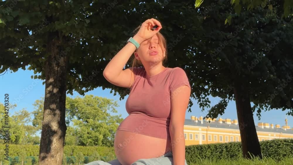 beautiful pregnant woman in 3rd trimester feels unwell outside, in the park in summer, lower back pain and hot