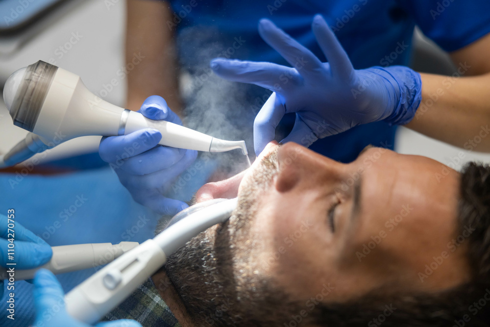 A dentist uses a vapor-emitting tool during a procedure, highlighting advanced dental techniques aimed at improving patient outcomes in a professional clinic setup. A dentist uses a vapor-emitting tool during a procedure, highlighting advanced dental techniques aimed at improving patient outcomes in a professional clinic setup.