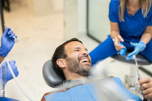 A male patient shares a light-hearted moment with dental professionals during his appointment, showcasing the importance of comfort and rapport in dental health care.