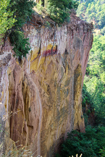 Ockerfelsen in den Farben Rot, Ocker, Gelb und Orange vor Wald und Bergen in Roussillon, Frankreich