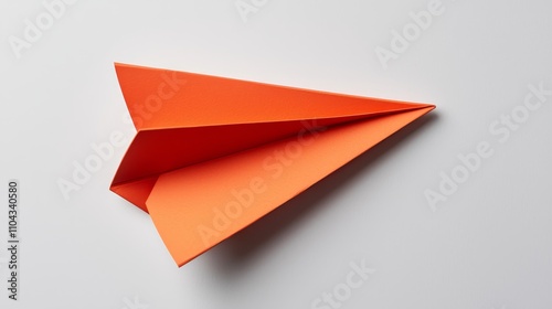 Wallpaper Mural  an orange paper airplane on a white surface, demonstrating how to make an origami airplane The paper airplane is folded in a way that creates a star-like shape, wi Torontodigital.ca