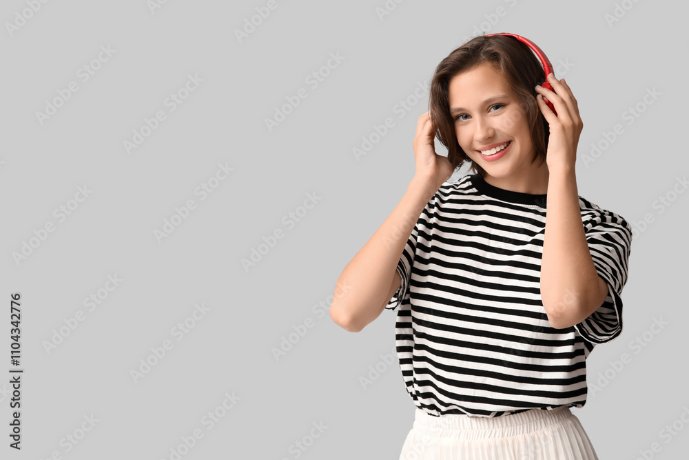 Smiling young woman in modern headphones on grey background Smiling young woman in modern headphones on grey background
