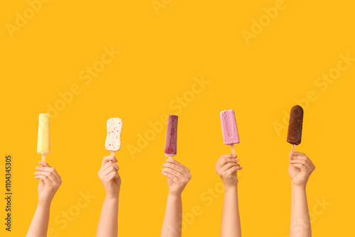Female hands with different sweet ice-cream on yellow background