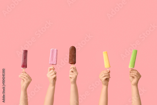 Female hands with different sweet ice-cream on pink background