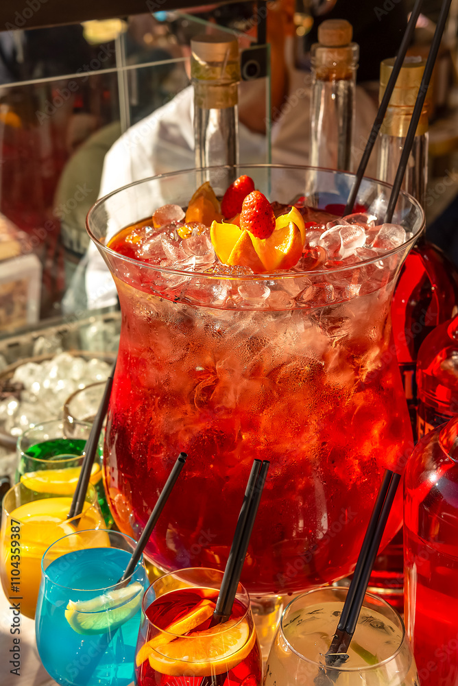 Street trade. Large glass vessel with sangria with ice and colorful cocktails in glasses on the counter
