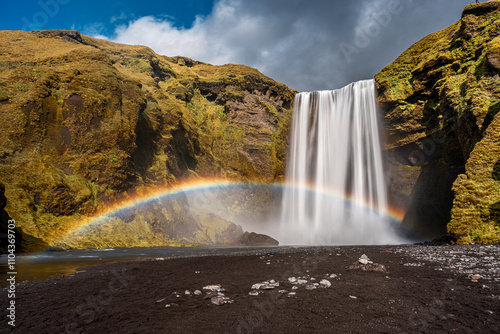 Enchanting picture of the iconic waterfall Skogafoss on iceland with mist and rainbow