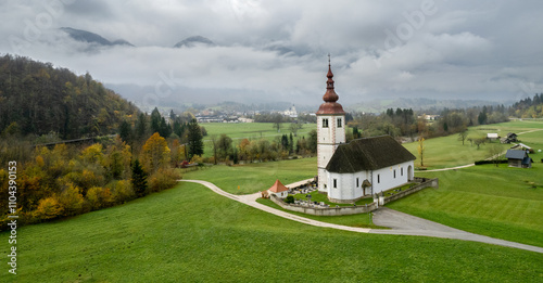 Church of st. John the baptist at bohinjska bela, slovenia, dominating the autumn landscape photo