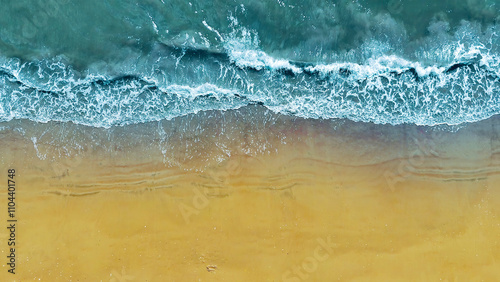 Aerial View of Waves on Sandy Beach. A stunning aerial perspective of ocean waves meeting a golden sandy beach, showcasing the natural beauty of the coastline.