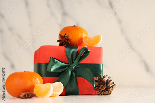 Sweet tangerines with gift box, star anise and forest bump on white table near grunge wall photo