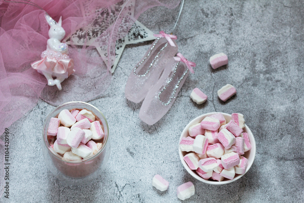 Cocoa with marshmallows, Christmas tree decorations and pink tulle on a concrete background.