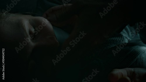 Lowkey closeup shot of unrecognizable criminal abducting young lady, closing her mouth with duct tape and putting sack on head, human trafficking and abuse