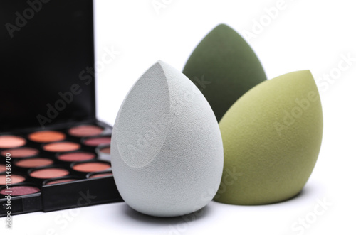 Egg makeup sponge and eyeshadow palette on white background photo