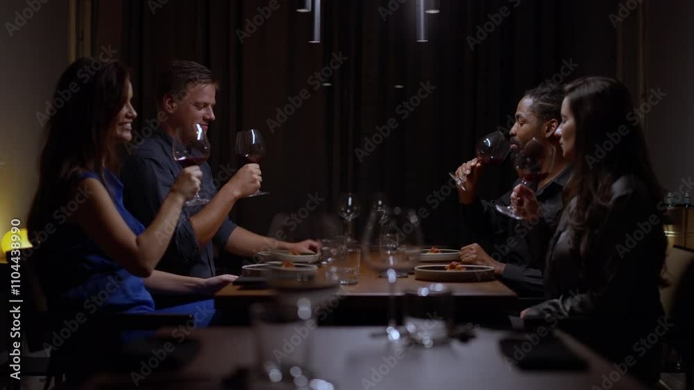 Happy friends celebrating Christmas or graduation together, having a dinner party, clinking their glasses with wine, talking and smiling Happy friends celebrating Christmas or graduation together, having a dinner party, clinking their glasses with wine, talking and smiling