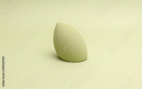 Egg makeup sponge. Blender for foundation on green background photo