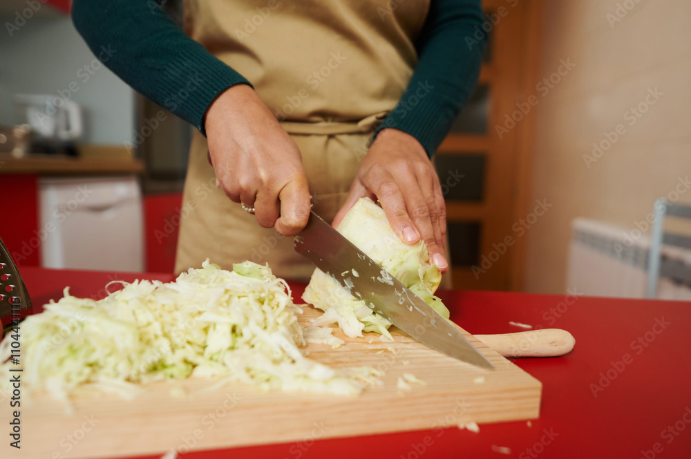 Person chopping fresh cabbage on wooden cutting board Person chopping fresh cabbage on wooden cutting board