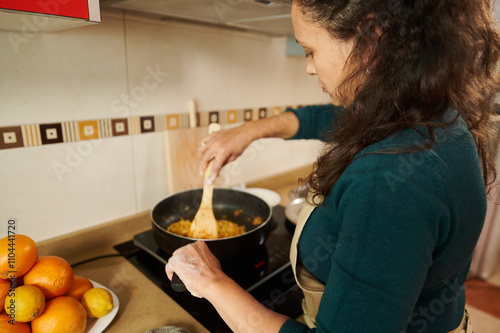 Woman cooking a meal on a stove in a cozy kitchen setting photo