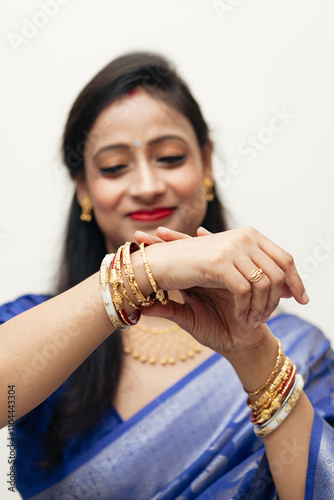 A joyful Bengali Indian woman from India, dressed in a traditional saree, is adjusting her bangles (Shaankha Pola). photo