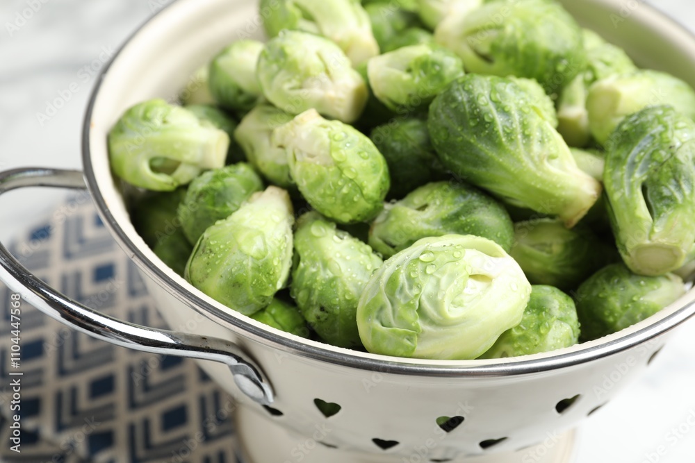 Fresh Brussels sprouts in metal colander on white marble table, closeup Fresh Brussels sprouts in metal colander on white marble table, closeup
