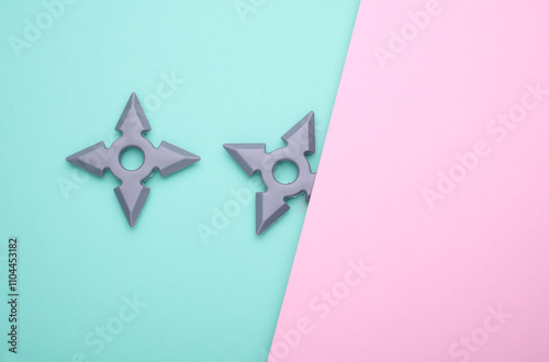 Toy plastic ninja shurikens on blue pink background photo