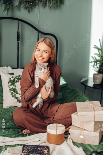 A beautiful woman at home near the Christmas tree with her beloved pet cat