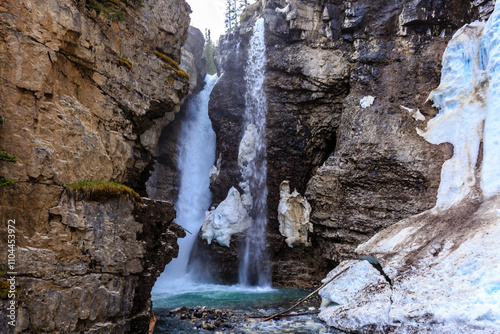 A waterfall is flowing into a river in a rocky canyon photo